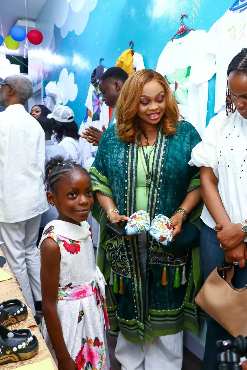 A child and an adult smiling beside a display of handmade crafts