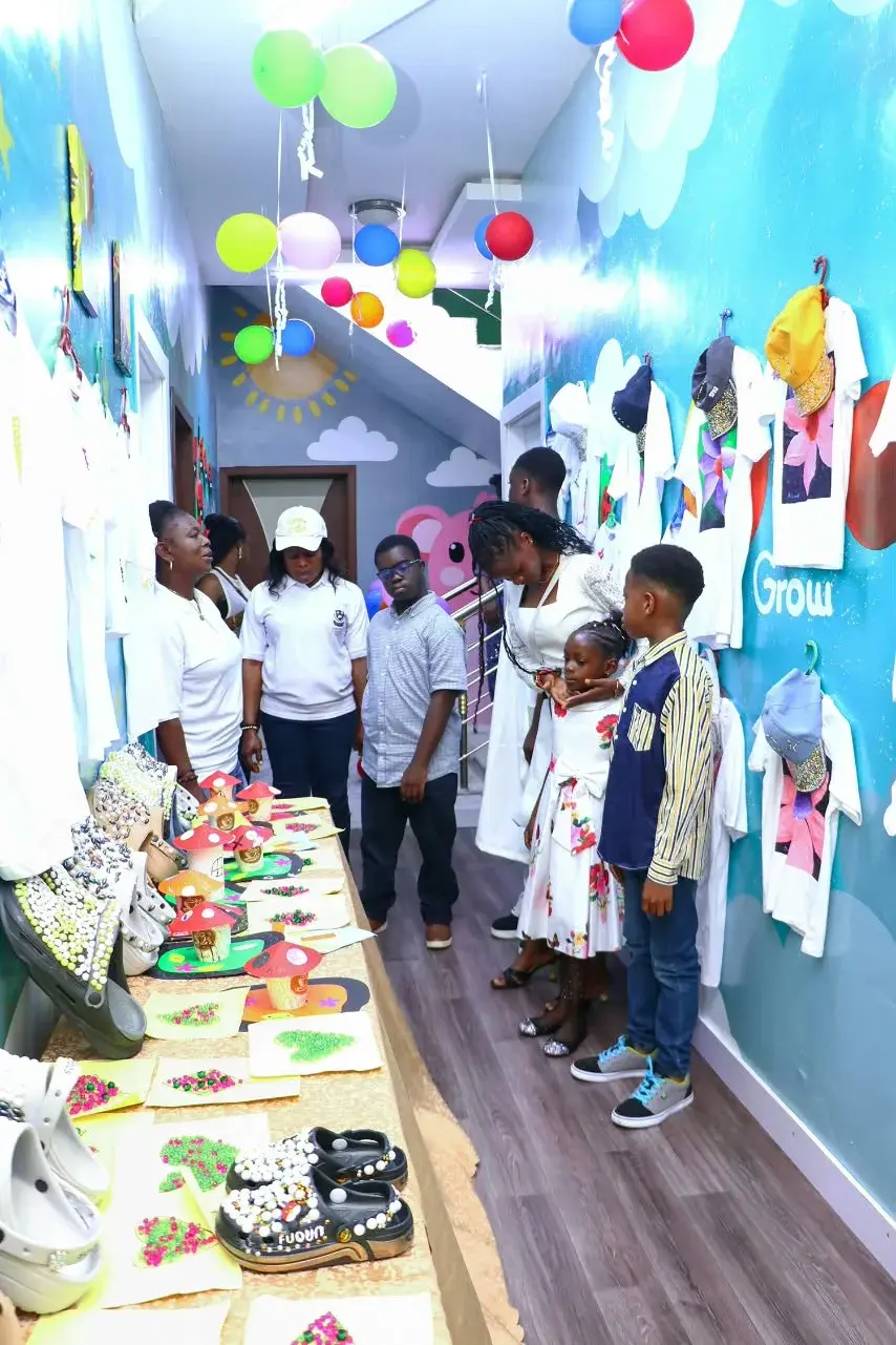 Children and adults gathered together beside a school arts and crafts exhibition