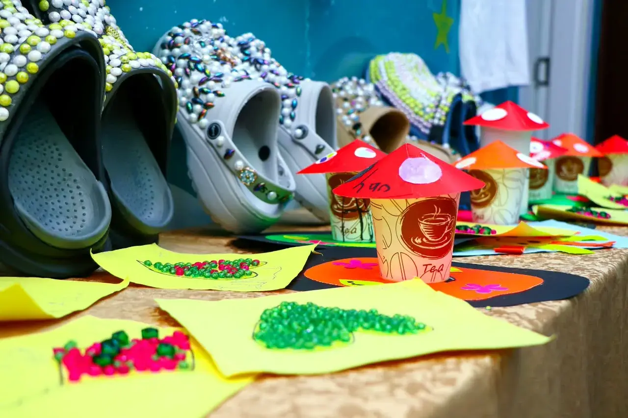 Colourful handmade mushroom models and decorated sandals on an exhibition table