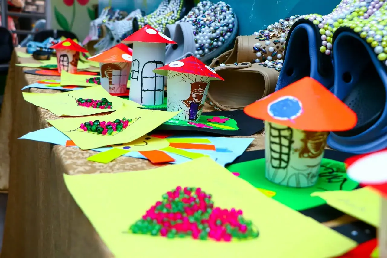 Paper craft models and colourful materials arranged on a display table